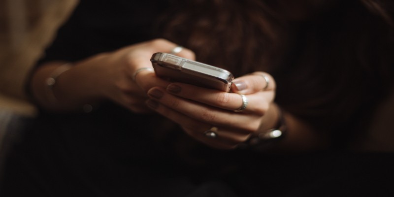 A close-up of a woman’s hands using a smartphone.