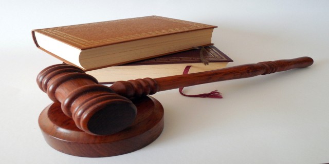 A judges gavel laying beside some law books.