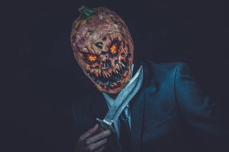 Hombre enmascarado con calabaza de Halloween y cuchillo