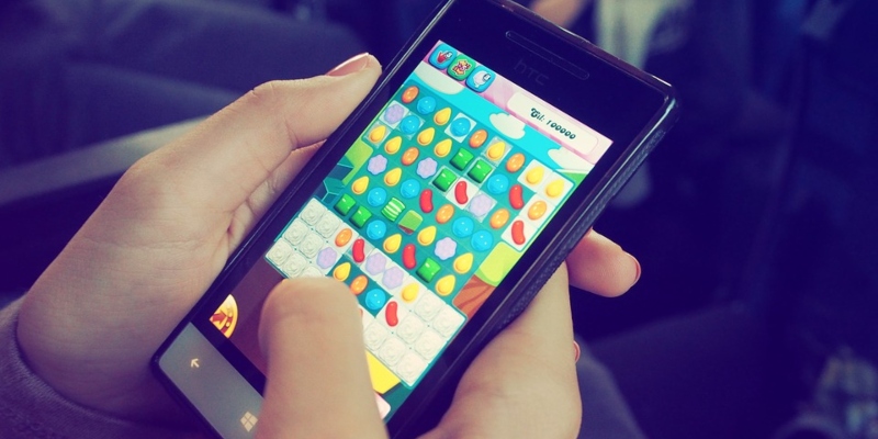 Woman playing Candy Crush on mobile phone; Spin Casino Blog