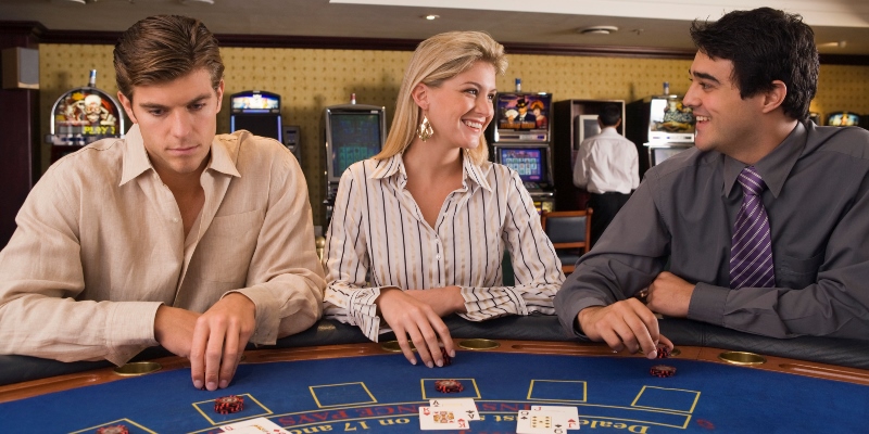 Deux hommes et une femme assis à une table de Blackjack