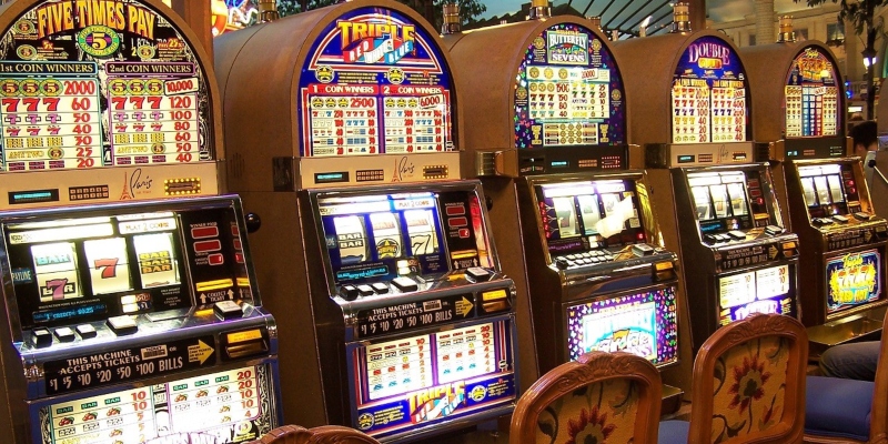 A line-up of five slot machines in a casino - Spin Palace Blog