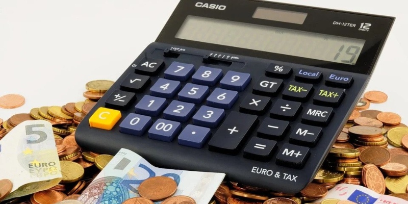 A calculator resting on a pile of money - Spin Palace Blog
