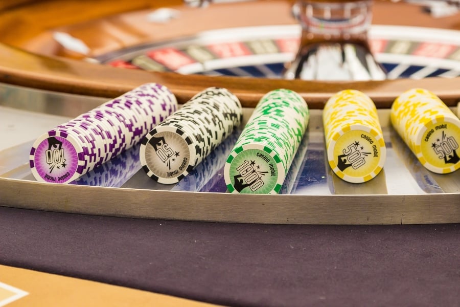 Casino chips laid out besides a Roulette wheel.