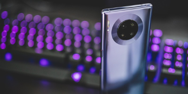 A Huawei smartphone in front of purple background lights