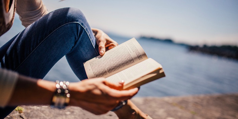 woman reading outside by water